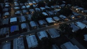 Aerial view of an American neighborhood at night, with neatly arranged homes with illuminated windows, showing peaceful ambiance of suburban living under a starry sky. Top down flyover shot. - Powered by Shutterstock - Get 15% off with code: PIKWIZARD15