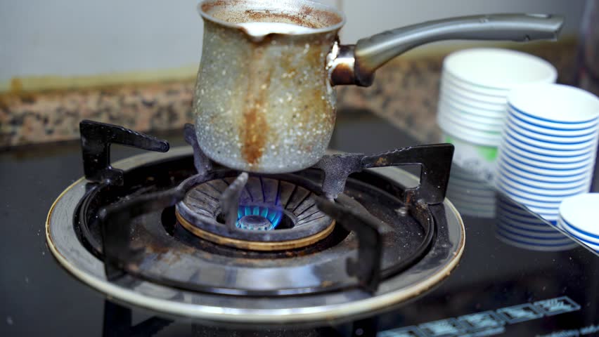 Old-style coffee pot boiling over a blue gas flame, evoking warmth, tradition, and daily kitchen rituals.