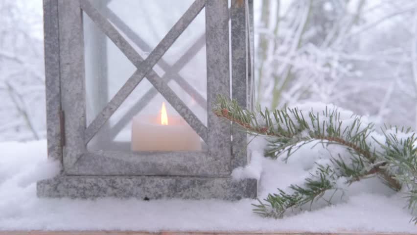 cozy Christmas scene with glowing candle in garden lantern lights up snowy scene, female hands holding winter decoration, perfect for bringing Christmas cheer to winter décor