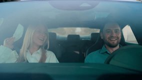 Blonde woman smiling and singing while man driving car. Glancing to side with focused expression. Relaxed passenger enjoying music during ride. Lifting hands together to song beat during trip. - Powered by Shutterstock - Get 15% off with code: PIKWIZARD15