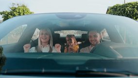 Excited woman singing song while sitting in passenger seat. Bearded man smiling and glancing toward her. Little girl in yellow holding teddy bear dancing in backseat. Enjoying upbeat music together. - Powered by Shutterstock - Get 15% off with code: PIKWIZARD15