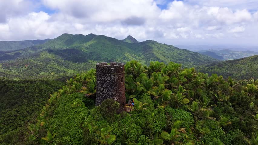 Cinematic drone footage showcasing the iconic observatory tower rising above an endless sea of lush green forest in El Yunque Rainforest, Puerto Rico