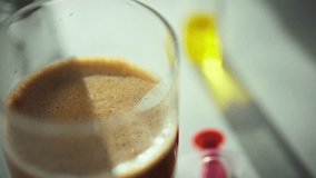 A scientist performs an experiment by carefully pouring a clear liquid into a glass beaker containing a brown substance. The laboratory is equipped with various scientific instruments - Powered by Shutterstock - Get 15% off with code: PIKWIZARD15