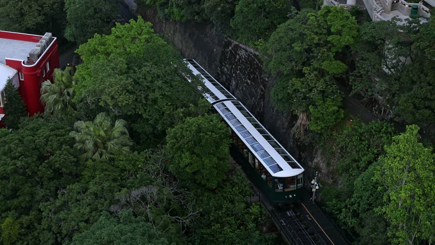 Top view of the famous green tram on the slope of Victoria Peak in Hong Kong passes, lifting visitors to the observation deck. High quality footage