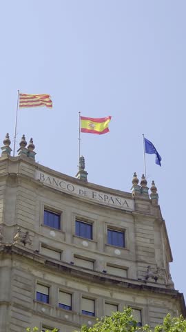 Flags of Spain and European Union waving on top of Banco de Espana building in Madrid