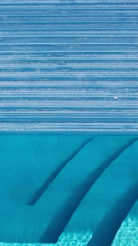 The automatic pool cover is halfway open, revealing clear blue water and built-in steps. Top-down view with geometric lines and clean structure
