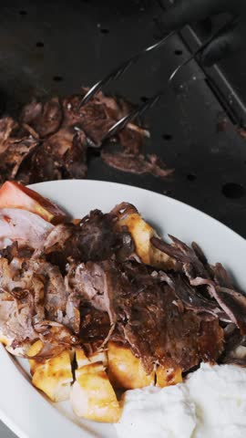 Fresh shawarma on a plate: crispy flatbread, grilled meat, and sauce. Meat being served on top. Close-up, dynamic shot, restaurant kitchen
