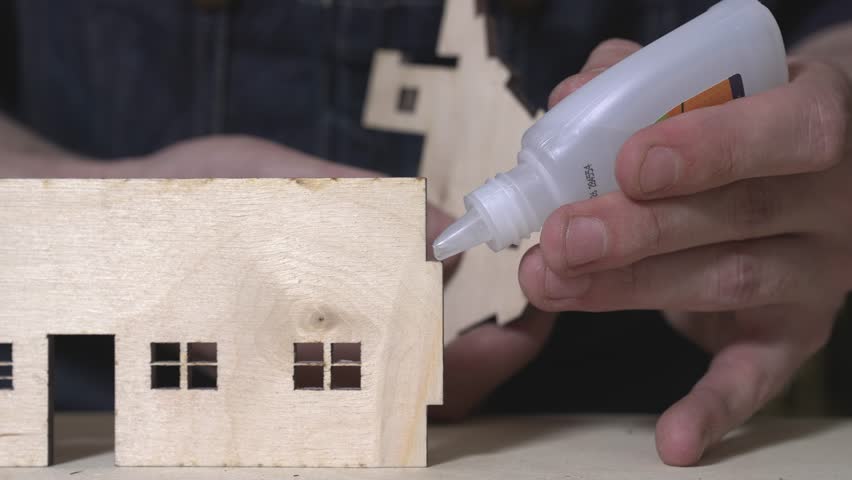 the worker laser cuts out parts of wood, makes a roof from an aluminum can, paints and patinas the future walls, glues everything together into one structure and the result is a miniature farmhouse