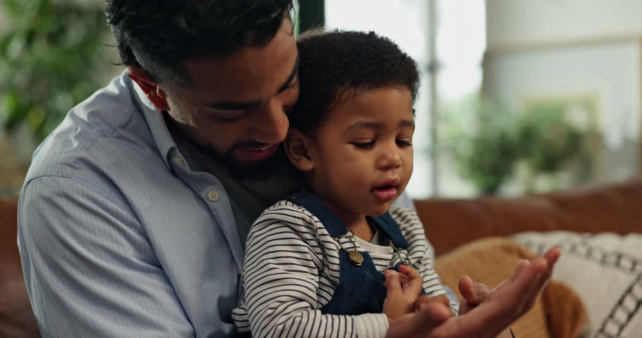 Bonding, game or holding hands with father and son on sofa in living room of home together. Development, love or security with boy child and single parent man in apartment for playful activity