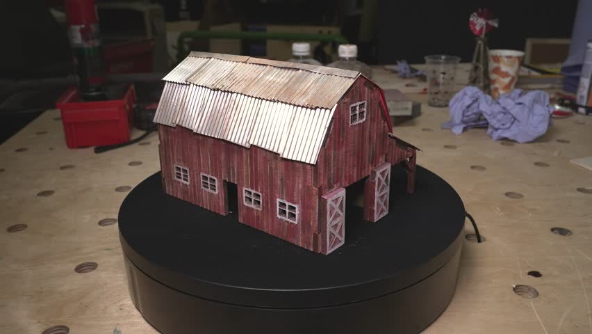 the worker laser cuts out parts of wood, makes a roof from an aluminum can, paints and patinas the future walls, glues everything together into one structure and the result is a miniature farmhouse