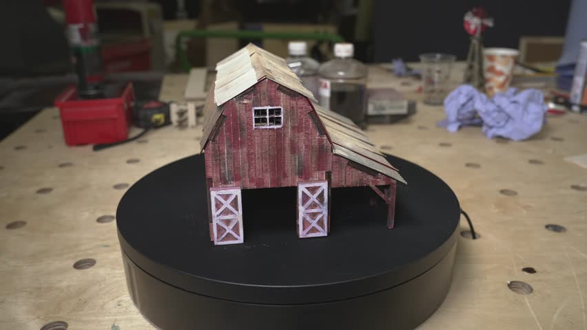 the worker laser cuts out parts of wood, makes a roof from an aluminum can, paints and patinas the future walls, glues everything together into one structure and the result is a miniature farmhouse