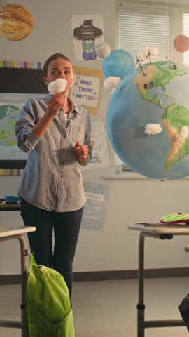 Female Teacher Educating Smart Kids During Science Lesson in Classroom. Primary School Boy Presenting Green Energy Sources in Front of Class Using Earth Model. STEM Education. Dolly Shot Vertical Shot