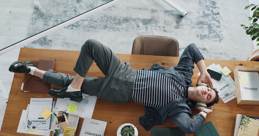 Above, headphones and relax with business man in office for streaming, song charts and sound. Music, radio performance and audio subscription with person and podcast in media agency for record label