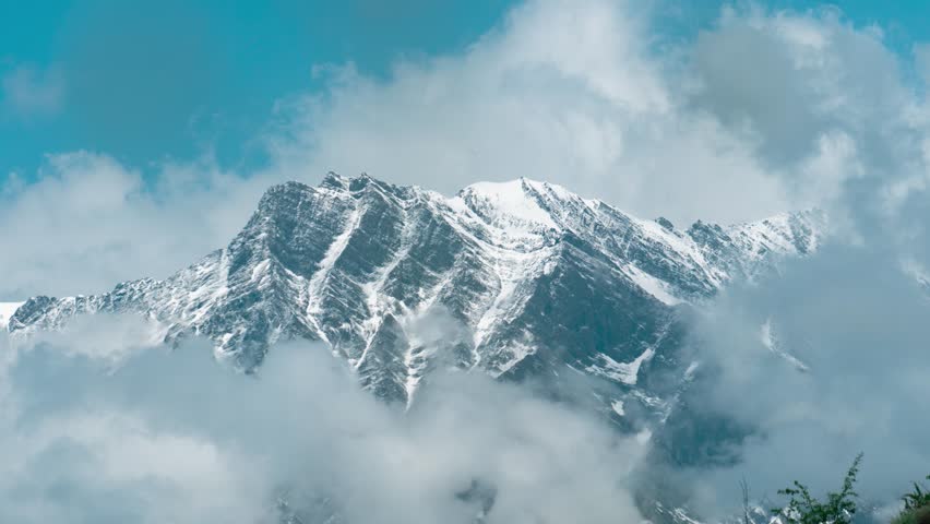 4K Zoom in timelapse of clouds cover snow mountain in Udaipur village in Himachal Pradesh, India. Monsoon clouds on high Himalayan peak. Nature landscape.