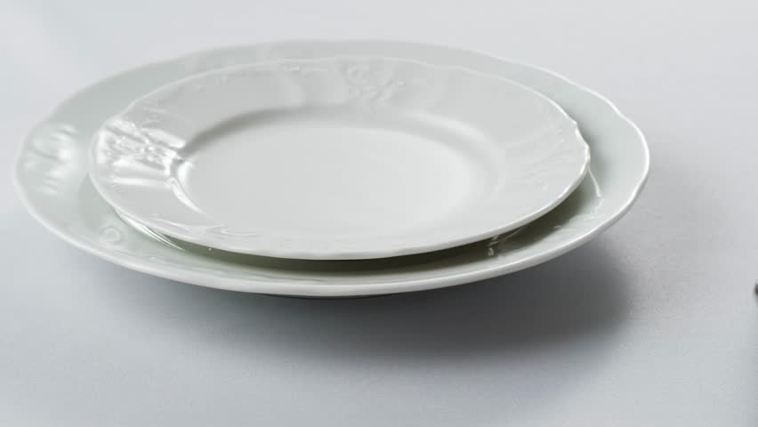 Elegant table setting with white tableware plates, cutlery, and glassware for a classy dining, fancy expensive restaurant dinner