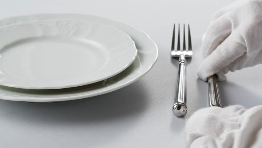 Elegant table setting with white tableware plates, cutlery, and glassware for a classy dining, fancy expensive restaurant dinner