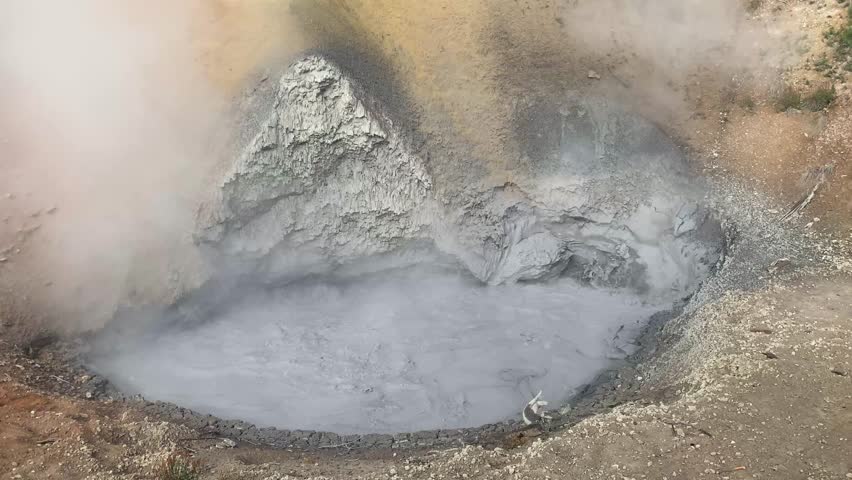 Bubbling mud pot geyser geothermal volcano feature steaming at Yellowstone National Park Wyoming USA