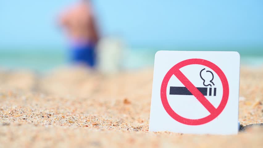 No Smoking sign. Smoking is prohibited in public places. Prohibitory sign against the background of sand and sea, ocean. Attention, smoking is prohibited.