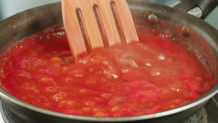 Chicken in tomato sauce is boiling on a frying pan with spices. Cooking tomato sauce curry with chicken fillet. Traditional Italian Mexican Asian dish. High quality studio shot for cafe, restaurant