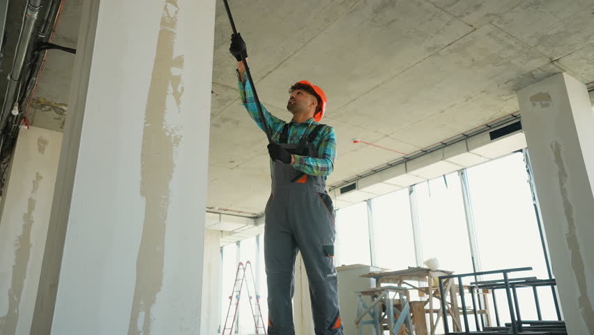 Painter priming walls in a building under construction