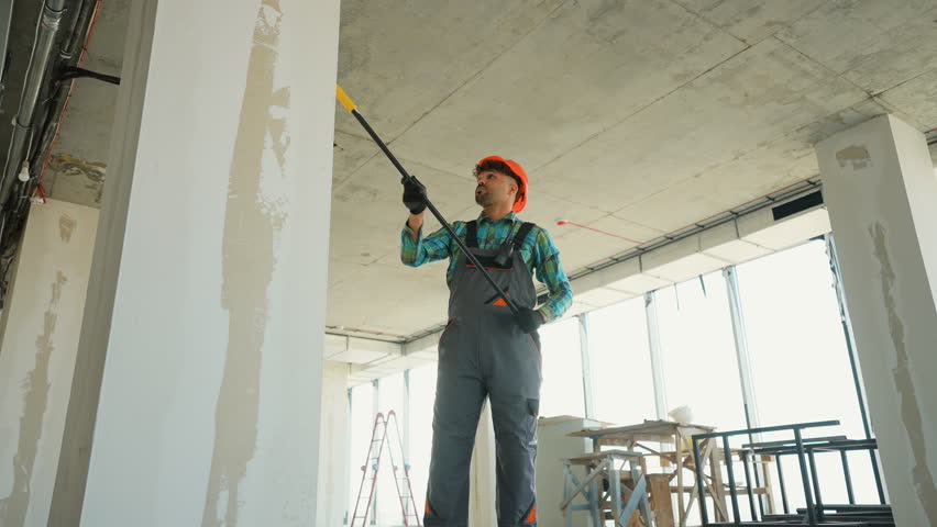 Painter priming walls in a building under construction