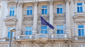 European union flag waving on building balcony. European union flag waving on a balcony of a building with columns and windows, representing the presence and activity of the eu within the member state - Powered by Shutterstock - Get 15% off with code: PIKWIZARD15