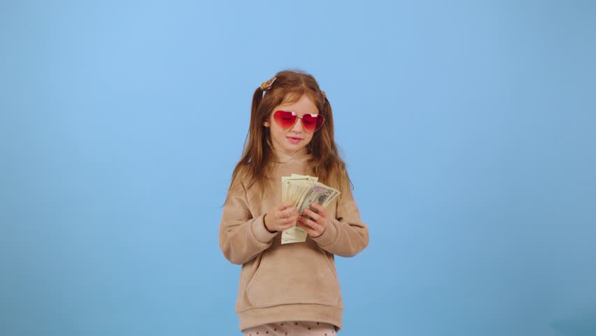 Child joyfully celebrating while cash bills are playfully thrown around in a vibrant blue background, showcasing happiness and carefree childhood moments
