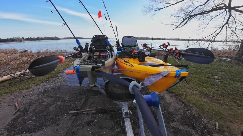 Truck pulling boat trailer with fishing kayaks. Water sport and fishing. Boat launch at lake in the wilderness. Boat trailer with fishing kayaks near drop off at the lake.