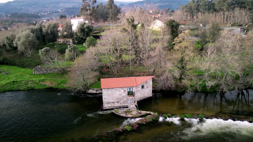Aerial view of water mill by river and greenery, Portugal.