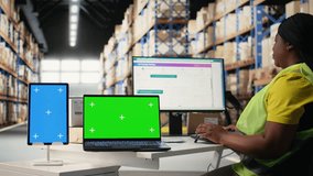Multiethnic team of warehouse workers next to green screen monitor. Managing shipping labels, barcode scanner data or e-commerce inventory tracking systems in industrial warehouse. Camera A. - Powered by Shutterstock - Get 15% off with code: PIKWIZARD15