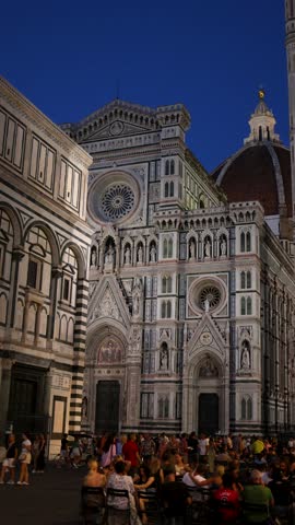 Florence - 09 14 2024: People gather at outdoor tables in front of the illuminated Florence Cathedral and Baptistery at night.