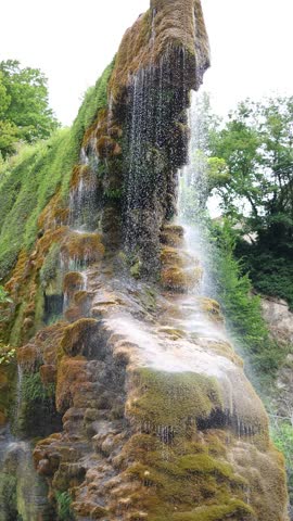 The Grotte di Labante waterfall flows over moss-covered rocks, creating a unique natural formation in the Italian Apennines
