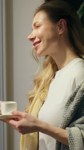 Relaxed happy Caucasian girl woman drinking coffee looking window morning peace at home resting homeowner female lady drink tea breakfast enjoying routine peace relaxation weekend indoors apartment