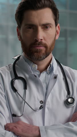 Experienced confident Caucasian man male doctor bearded guy therapist doc radiologist stethoscope in white coat uniform looking at camera crossing arms folded hands indoors hospital laboratory clinic