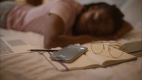 Sleeping napping African American woman female girl writer student lying down on bed sleep nap tired study calling mobile phone on book no sound don't hear call smartphone at home bedroom late night - Powered by Shutterstock - Get 15% off with code: PIKWIZARD15