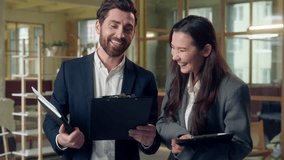 Laughing Caucasian Korean business workers talking documents clipboard analyzing at office partners coworkers man woman managers businessman businesswoman speak discuss marketing financial report data - Powered by Shutterstock - Get 15% off with code: PIKWIZARD15