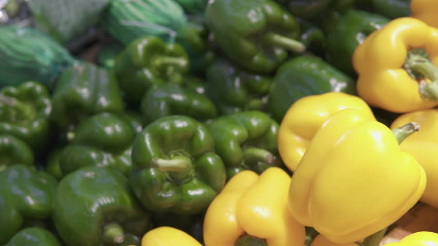 Closeup view of fresh bell peppers in a grocery store. Ripe green, red and yellow vegetables. Sweet pepper is a healthy vegetarian food. Product of organic farming.