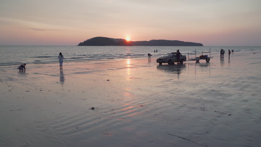 Langkawi, Malaysia - 10 April, 2023: Awesome sunset view of Cenang Beach (Pantai Cenang) on Langkawi island. The sun is reflected in the sea and wet sand. Amazing seascape.