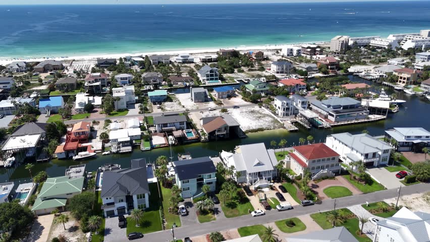 Panoramic drone movement over the center of coastal residential neighborhood with homes and green yards, Destin, Florida, USA
