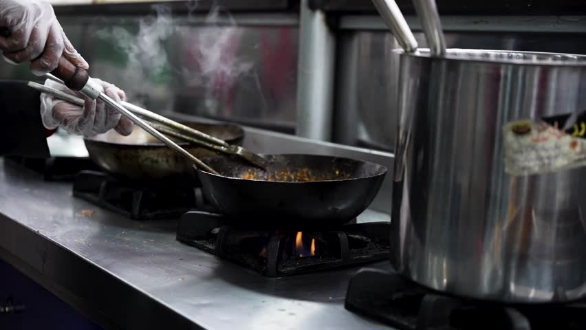 Close-up of chicken karahi being stirred in a hot pan over flame