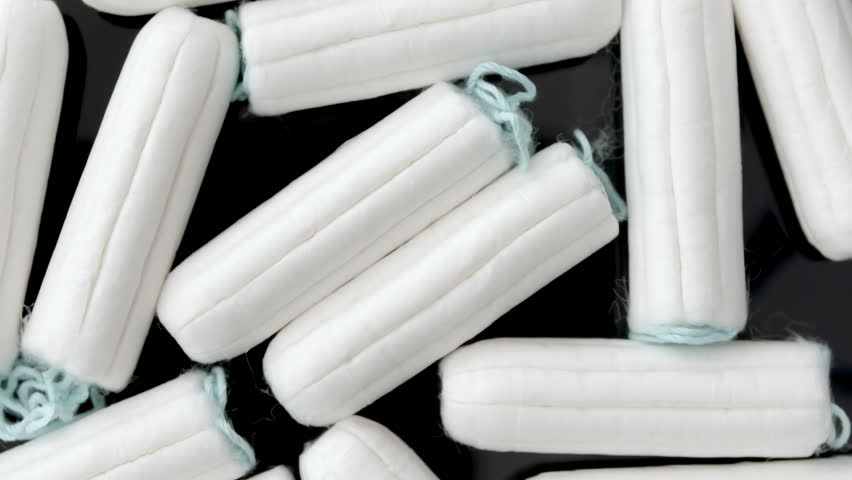 Multiple tampons rotate on dark floor with clean lighting and soft shadows, for hygiene product promo