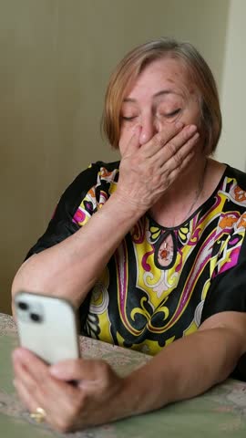 Elderly senior mature woman is using mobile phone, online video call talk, greeting her relatives and grandchildren. She is sad, missing her family, and remembering the past