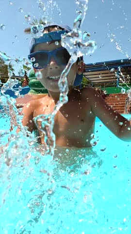 Summer pool enjoyment capturing young boy splashing, playing energetically in bright blue water with vibrant joy and carefree spirit