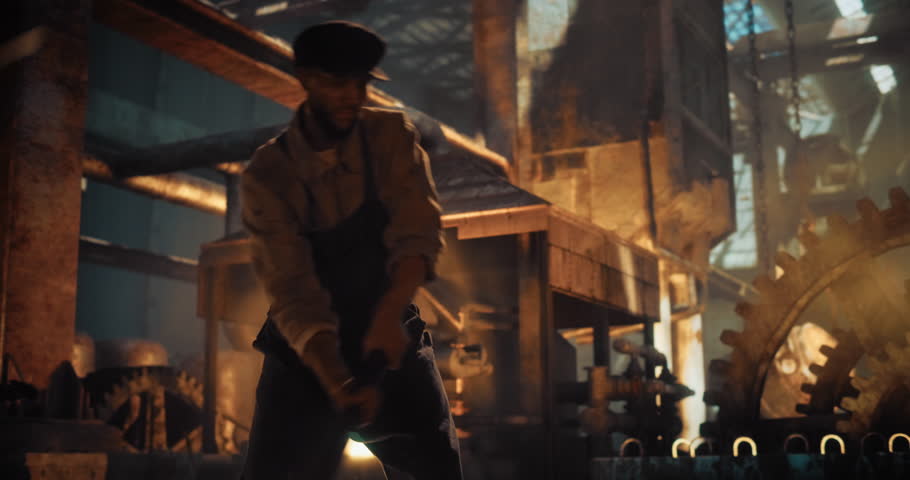 Caucasian Male Worker in Historical Ironworks Footage Using a Sledgehammer for Work at an Iron Foundry. Man Using Brutal Physical Force and Craftsmanship of the Early Industrial Era