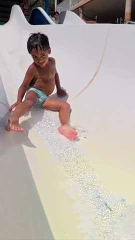 Child sliding down water slide into sparkling pool, experiencing pure summer happiness and playful excitement while enjoying refreshing aqua splash