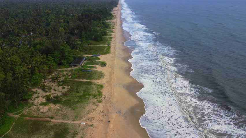 Aerial 4K drone view of the stunning coastline of Alappuzha (Alleppey), Kerala, India, showcasing the tranquil Arabian Sea, golden sandy beach, and lush greenery of this tropical paradise.	
