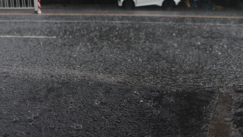 rain falling on the asphalt and cars passing through the puddles.
