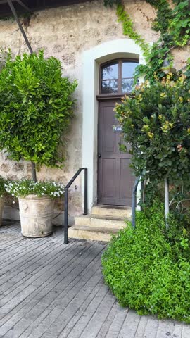 The main door to an apartment building with a plant and shrubs around