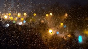 Blurred City Lights at Stormy Night with Lightnings Seen Through a Skyscraper Window with Rain Drops. Raindrops On Glass Window Against Night City Street During Thunderstorm. Melancholy Rain. - Powered by Shutterstock - Get 15% off with code: PIKWIZARD15