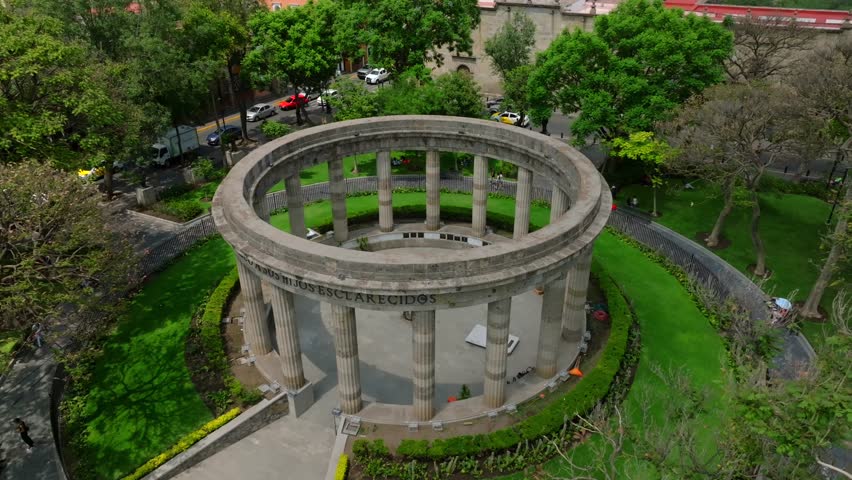 Slow motion aerial overlooking the circular Rotonda de los Jaliscienses Ilustres art monument with its tall columns Guadalajara, Mexico